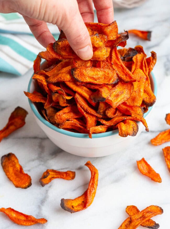 carrot chips Hand grabbing some carrot chips out of a bowl.