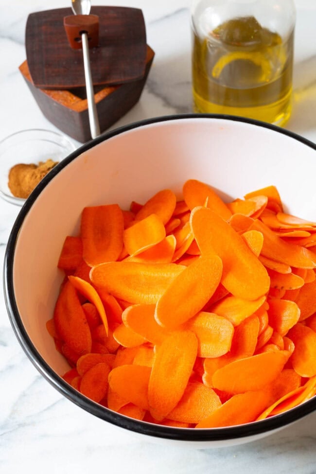 healthy chips Sliced carrots in a mixing bowl.