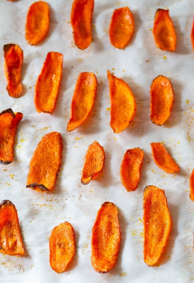 carrot recipes Carrot chips on a baking sheet lined with parchment after being baked.