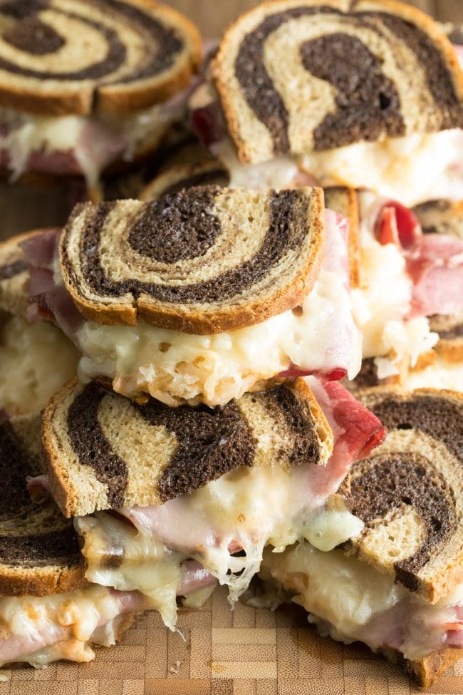 Baked Reuben sandwich recipe stacked on top of each other on a wooden background.
