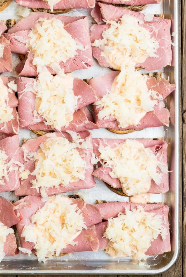 Bread topped with corned beef and sauerkraut on a sheet pan.