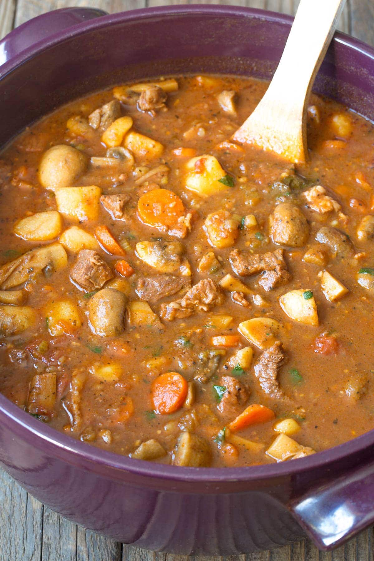 How to Make Beef Stew #ASpicyPerspective #BeefStew #BeefStewRecipe #Stew #StewRecipe #Beef #Crockpot #InstantPot #Stovetop #BeefStewCrockpot #SlowCookerBeefStew #BestBeefStew #HowtoMakeBeefStew Beef stew recipe in a large pot with a wooden spoon.