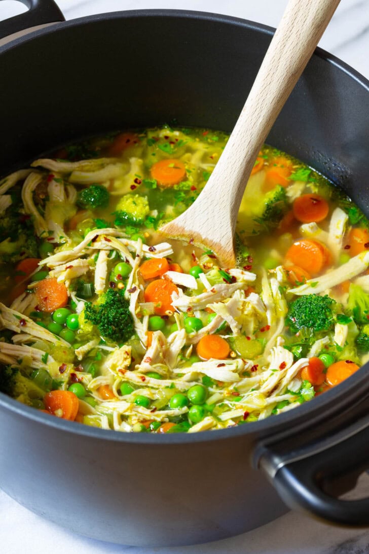Chicken Soup #ASpicyPerspective #ChickenSoup #DetoxSoup #ChickenSoupRecipe #ChickenDetoxSoup #Cleanse #Detox #Paleo #GlutenFree #DairyFree #Soup Pot of chicken soup with a wooden spoon stirring it.