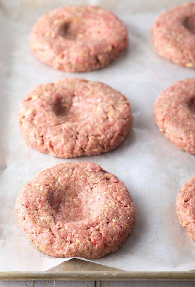 Hamburger patties with dents on top before being cooked.