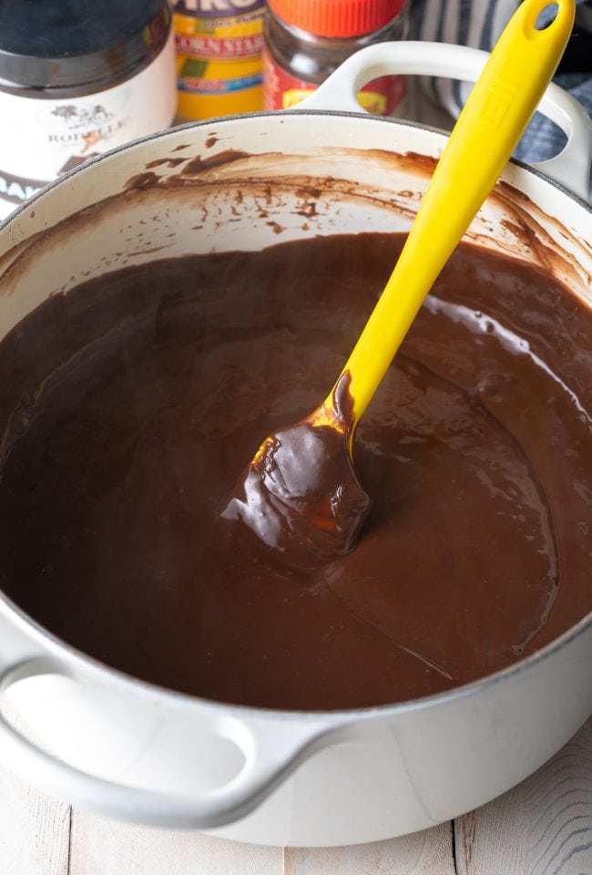 Stirring the chocolate pudding to melt the butter into the mixture in a large pot.
