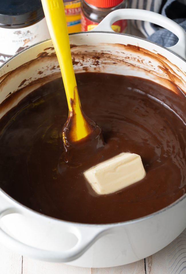 Chocolate pudding in a large pot with a chunk of butter in it.