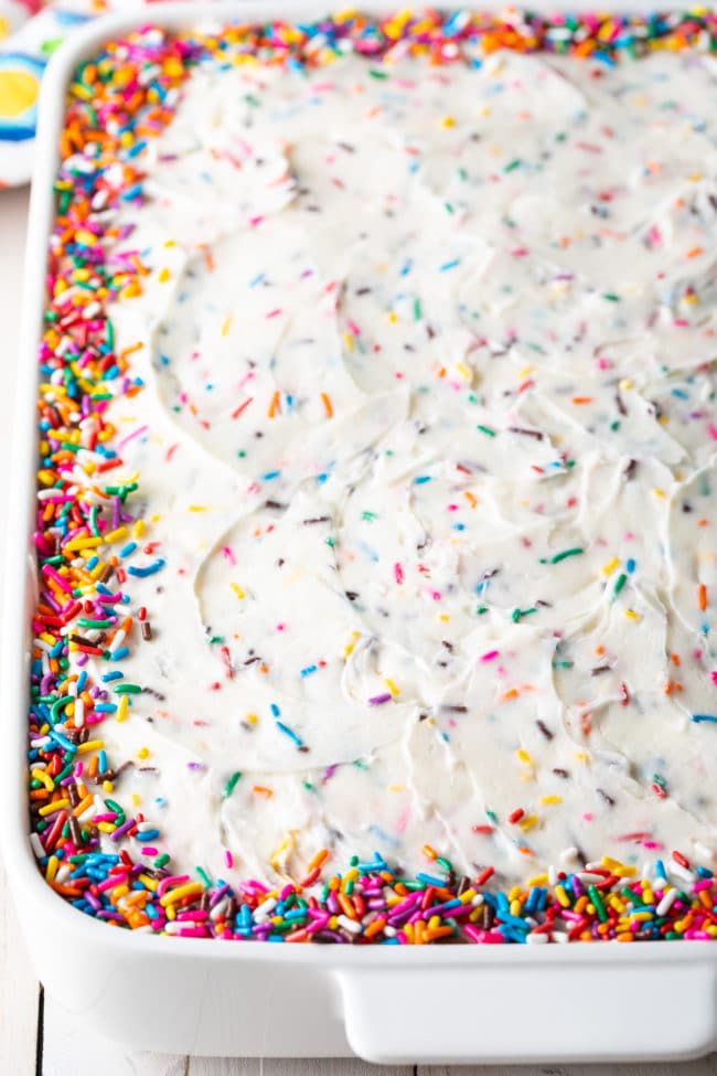 Vanilla birthday cake in a baking dish with colorful sprinkles around the edges.