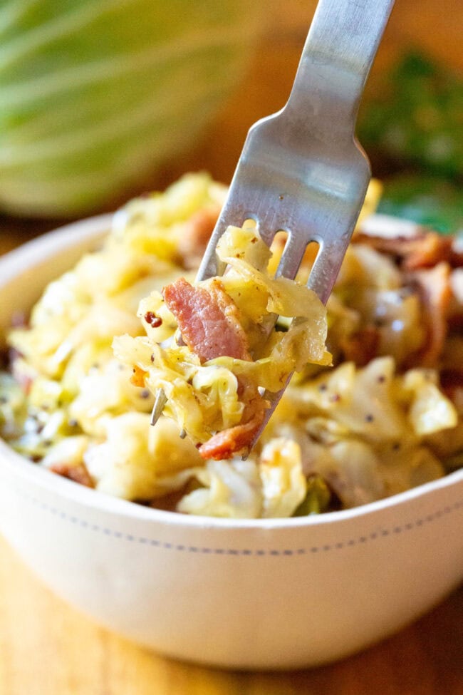 Amazing 5-Ingredient Irish Cabbage and Bacon Recipe for Saint Patrick's Day! #ASpicyPerspective #IrishCabbageBacon #Irish #Cabbage #Bacon #StPatricksDay #Dinner #SideDish Boiled Cabbage Recipe in bowl with forkful coming up