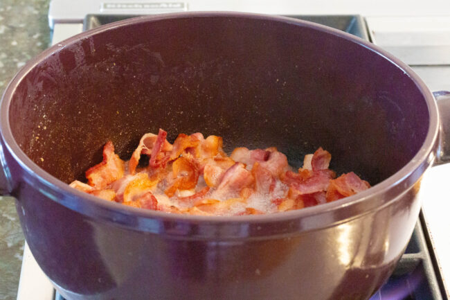 Making Irish Cabbage and Bacon Recipe for Saint Patrick's Day! #ASpicyPerspective #IrishCabbageBacon #Irish #Cabbage #Bacon #StPatricksDay #Dinner #SideDish Bacon cooking in a large pot on the stove.