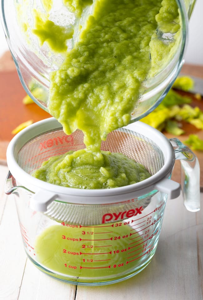 Celery pulp being strained in a measuring cup.