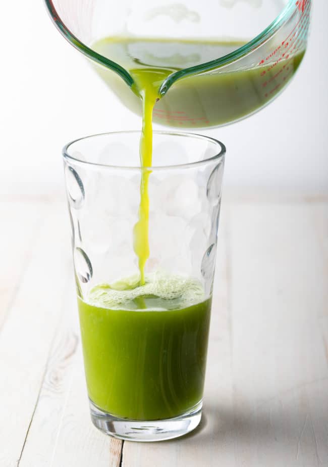 Pouring the celery juice from the measuring cup into a glass.