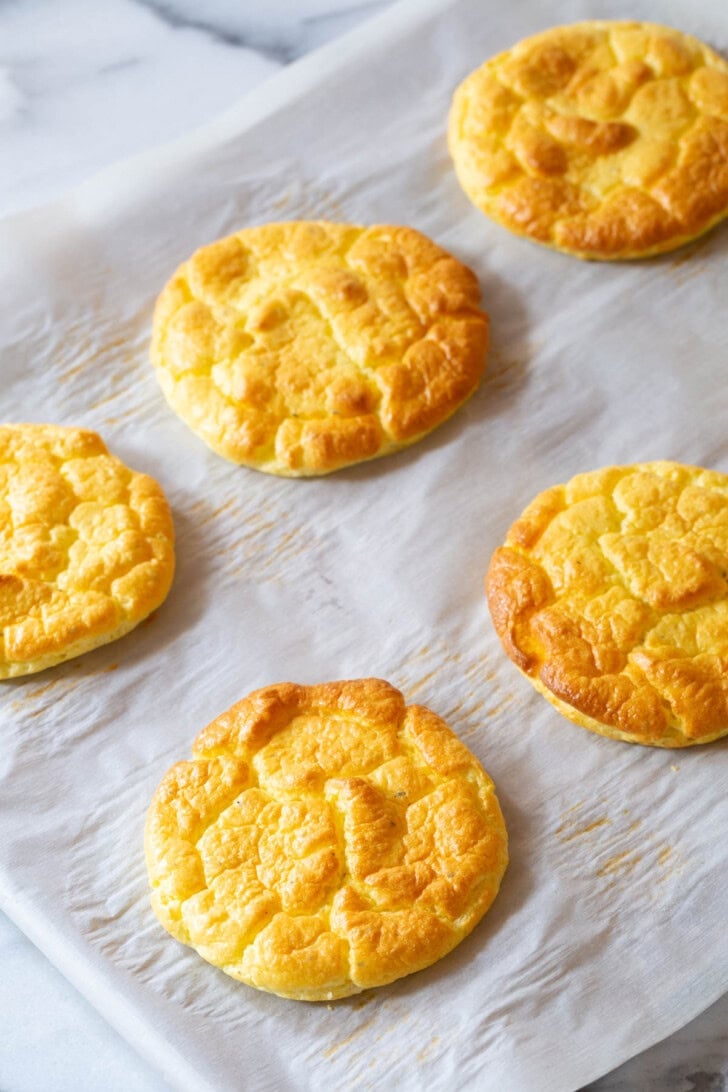 Keto Cloud Bread #ASpicyPerspective #LowCarb #GlutenFree #GrainFree #Keto #CloudBread #CloudBreadRecipe #KetoCloudBread #NoCarbBread Cloud bread on a baking sheet lined with parchment paper after being baked.