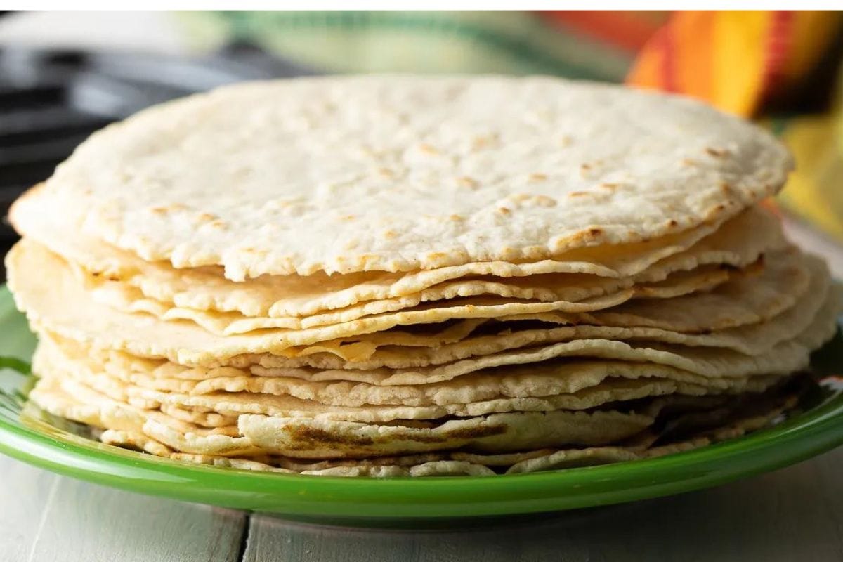 Stack of homemade tortillas on a green plate.