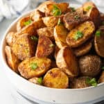 Bowl of crispy oven roasted potatoes sprinkled with fresh parsley.
