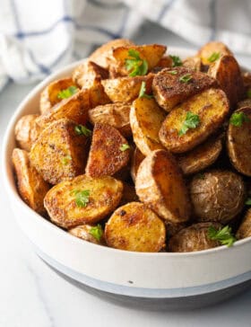 Bowl of crispy oven roasted potatoes sprinkled with fresh parsley.
