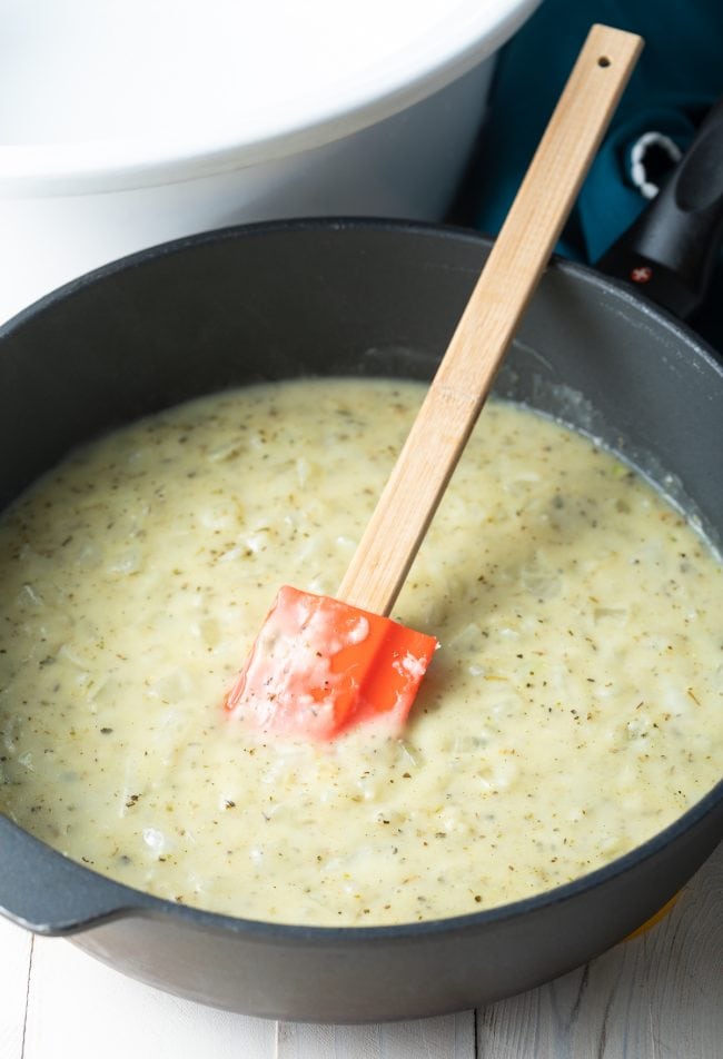 Gravy cooking in a skillet with a rubber spatula.