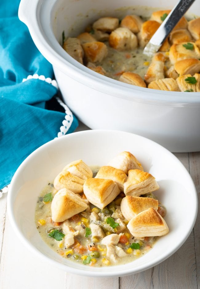 Crock pot chicken pot pie served in a white bowl with pieces of biscuits.