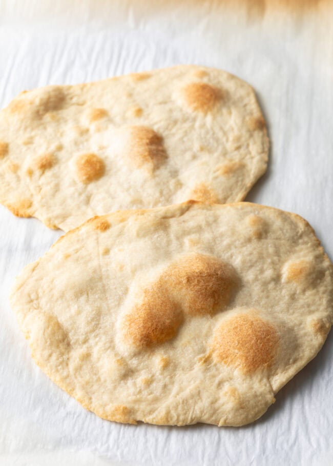 Two pieces of unleavened bread laying on a gray background.