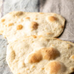 Two pieces of unleavened bread laying on a gray background.