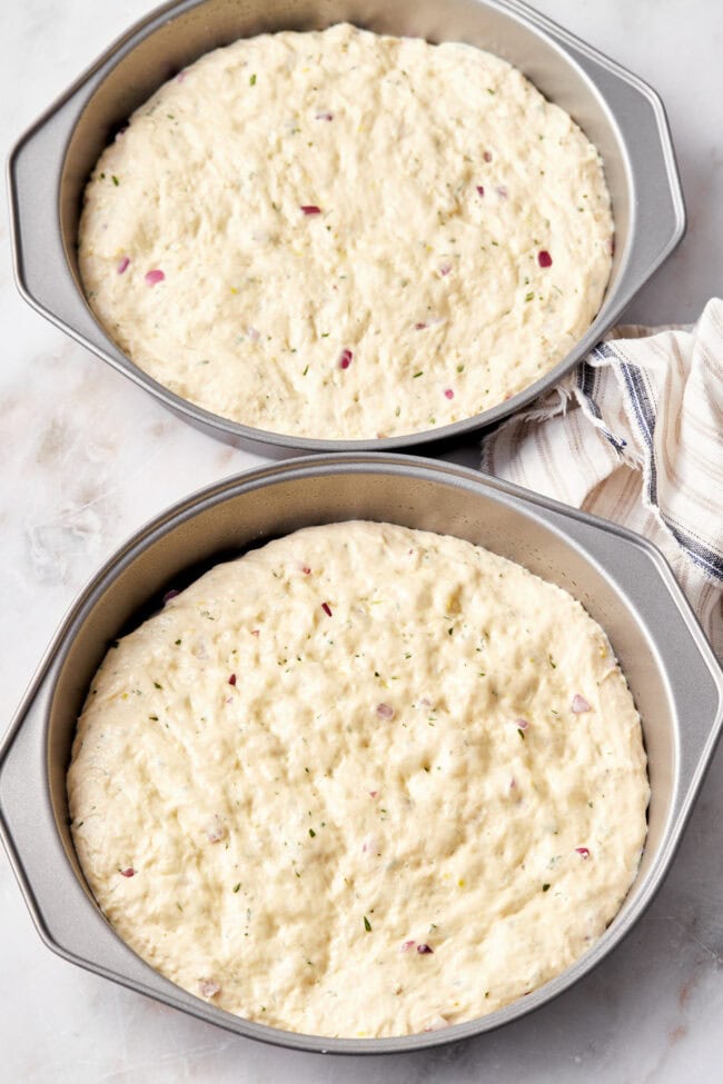 Focaccia dough in a cake pan before being baked.