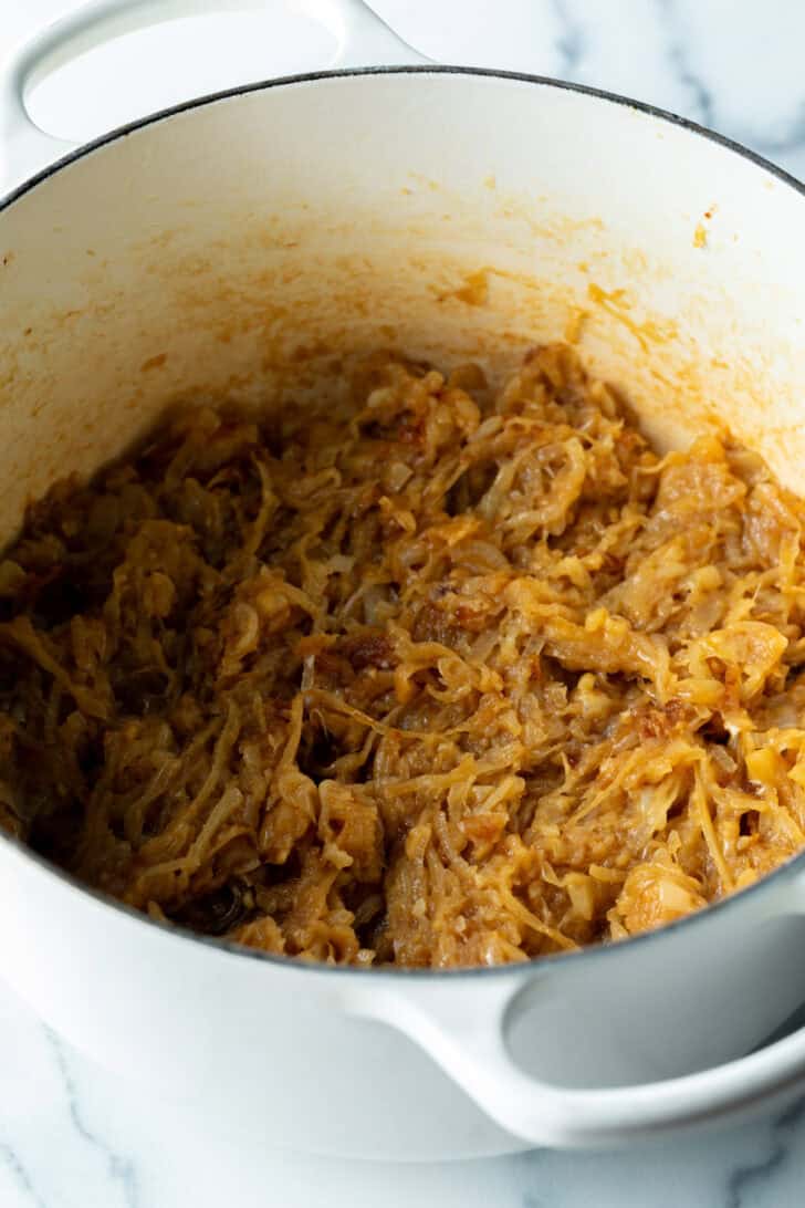 Large cooking pot with lots of caramelized onion slices.