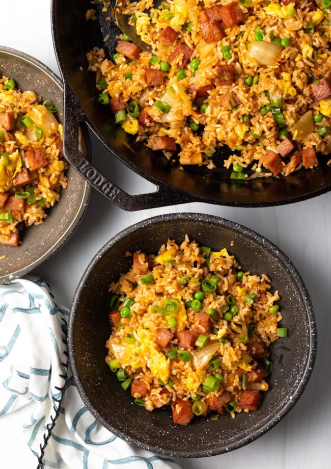 Spam fried rice served in bowls with more in a skillet next to them.