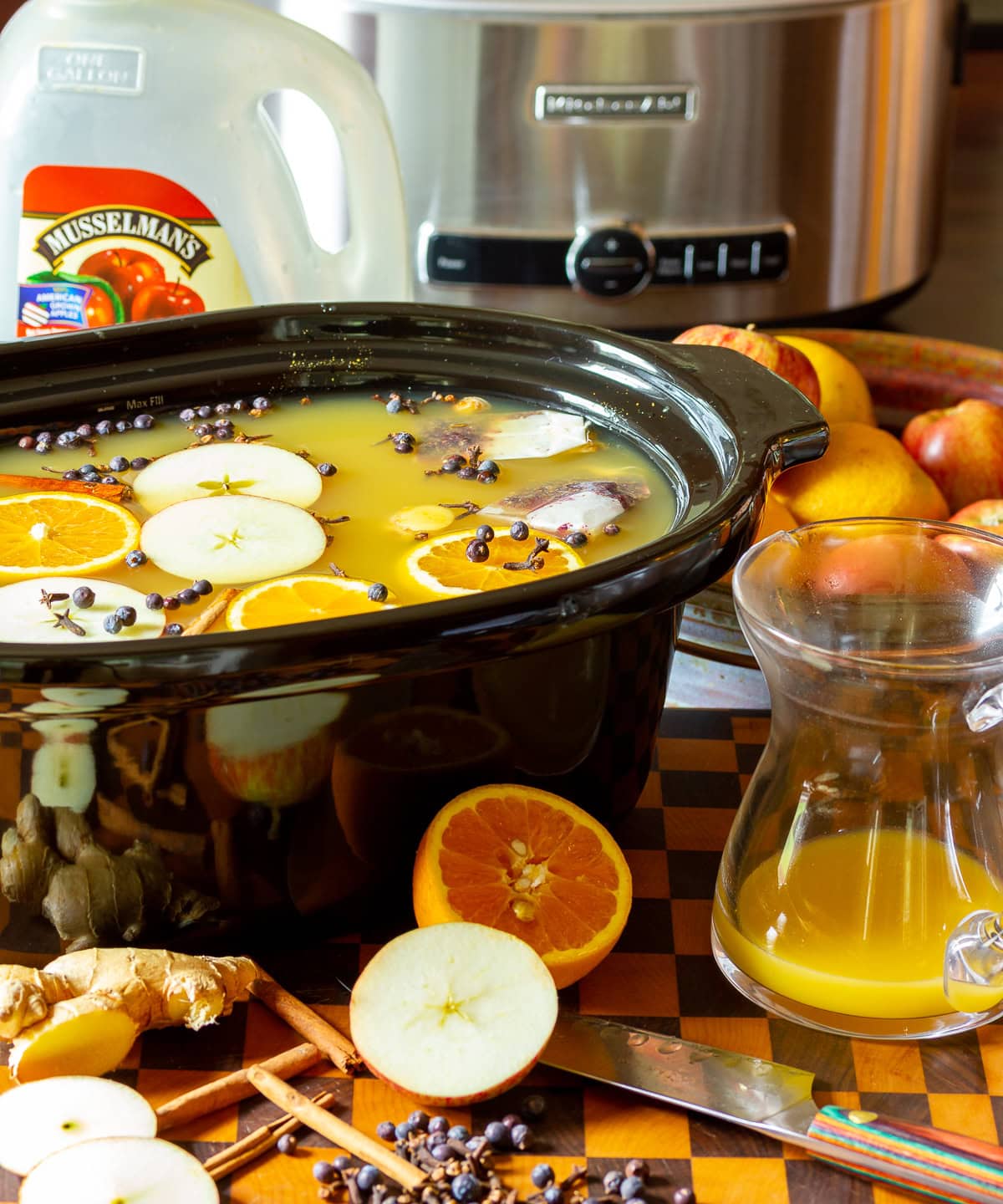 hot-apple-cider Apple cider wassail recipe in a crock pot with ingredients scattered in front.