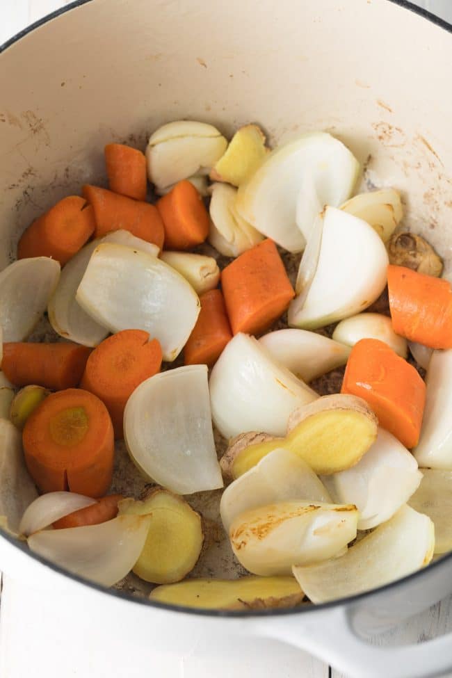 Carrots, onions, garlic and ginger being sautรฉed in a large stock pot.