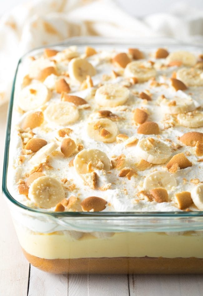 Banana pudding layer cake with whipped cream and fresh bananas on top.