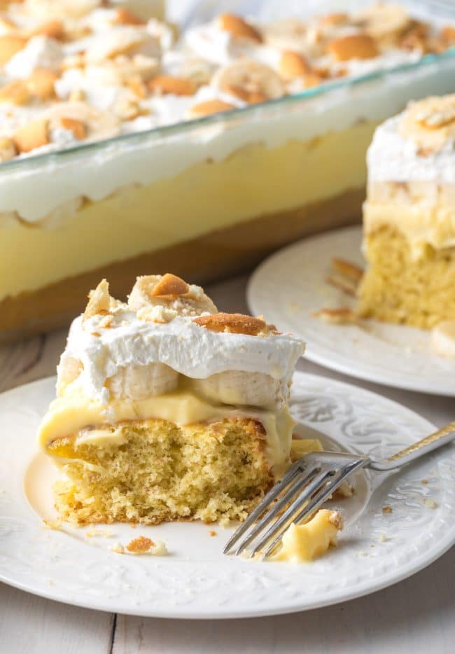 Best banana pudding cake slice on a plate next to another plate with cake on it, too.