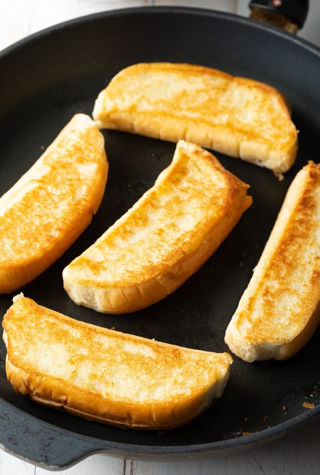 New England Buns being toasted in butter in a skillet. 