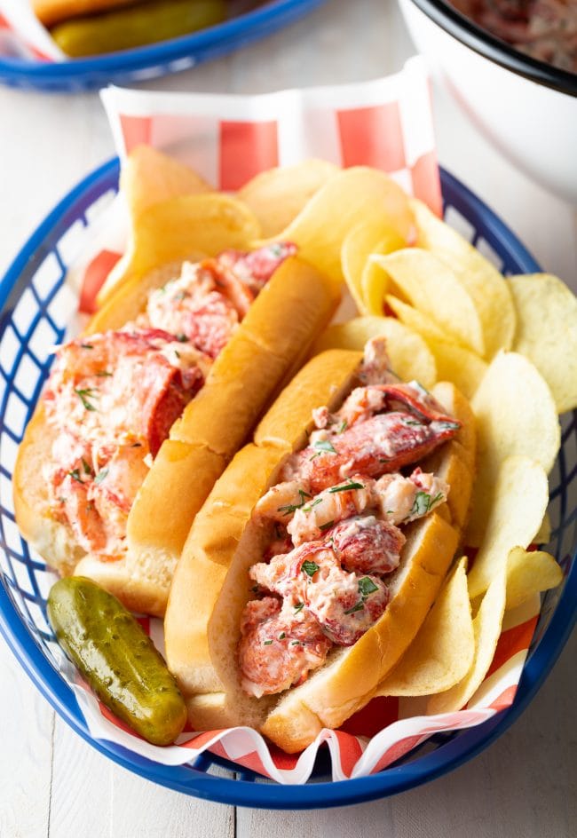 Lobster Rolls in a basket with chips and pickle. 