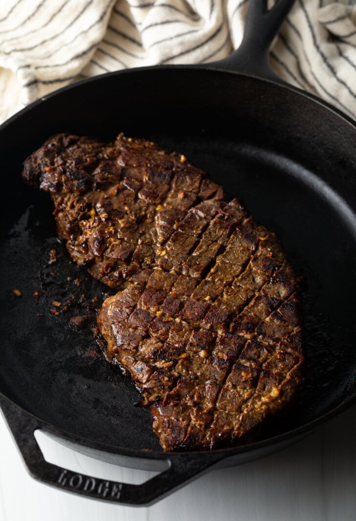 Searing the scored London broil is a large cast iron skillet.
