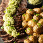 London broil sliced into thick strips, covered with rich green sauce and chopped scallions with baby potatoes on the side.