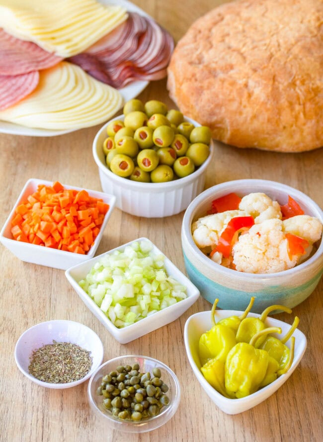 Ingredients you will need for muffaletta sandwich on a wooden background.