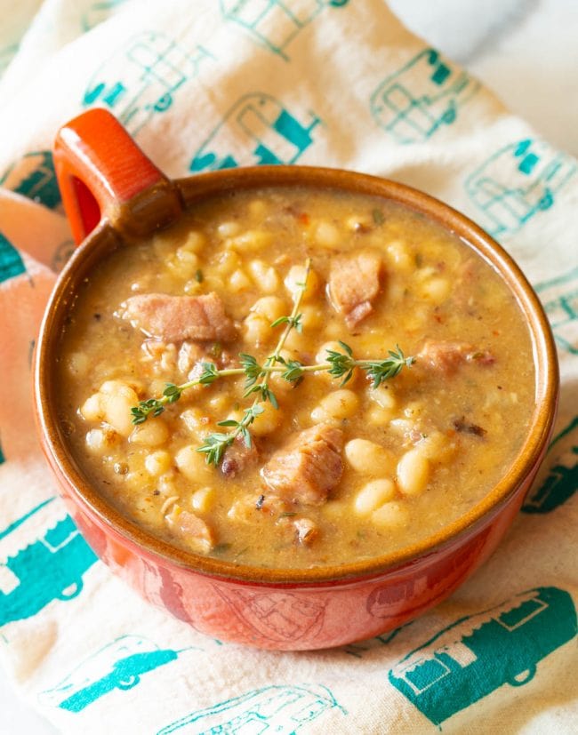 Ham and Bean Soup #ASpicyPerspective #HamAndBeanSoup #NavyBeans #HamAndBeans #NavyBeanSoup #BeanSoup #Soup Single serving of this ham and bean soup recipe with a fabric napkin in the background
