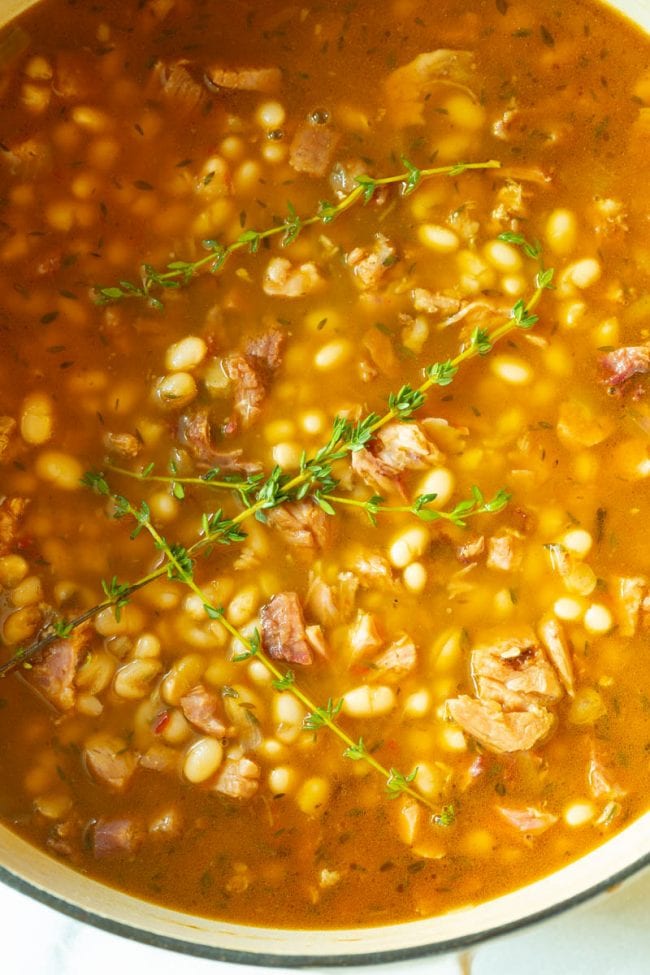 Ham and Bean Soup #ASpicyPerspective #HamAndBeanSoup #NavyBeans #HamAndBeans #NavyBeanSoup #BeanSoup #Soup Ham and Bean Soup - Top view of the pot full topped with some sprigs of thyme leaves