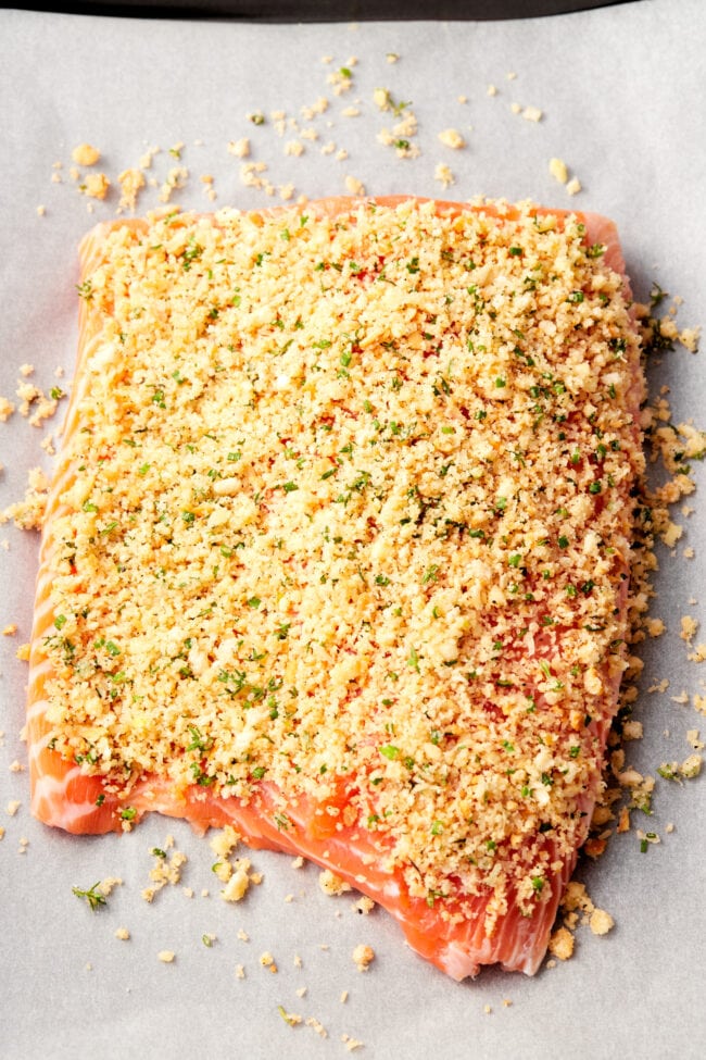 Parmesan Crust #ASpicyPerspective #Salmon #BakedSalmon #OvenBakedSalmon #SalmonRecipe #BakedSalmonRecipe #OvenBakedSalmonRecipe #HowtoBakeSalmon #ParmesanCrust #Fish #Dinner #MainDish Parmesan Crusted Salmon - Baked Salmon with parmesan crust on parchment paper before being baked.