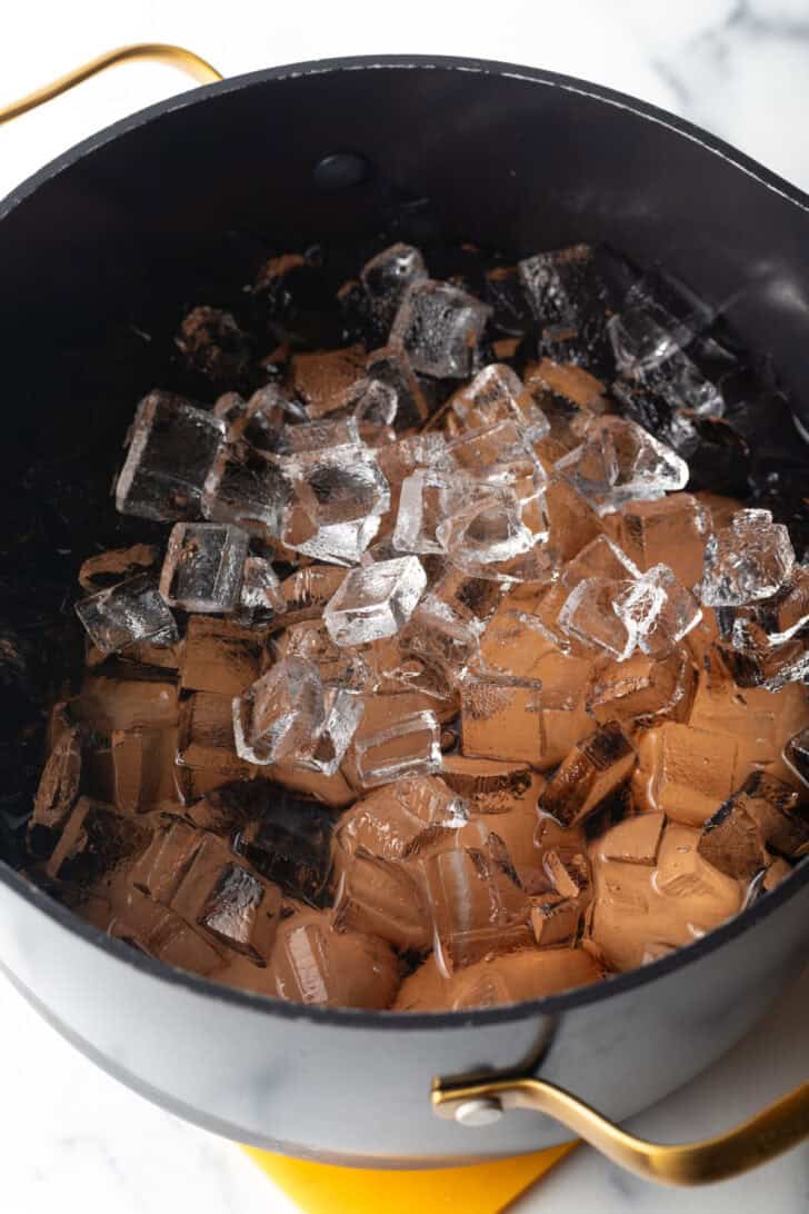 Large black pot of eggs, covered in ice cubes.