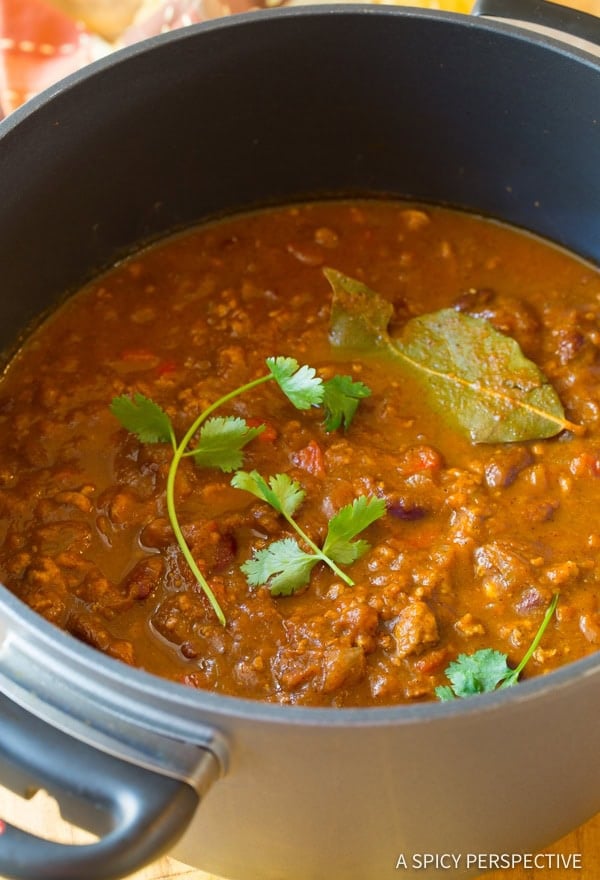 Pot of pumpkin chili recipe with cilantro and bay leaves.