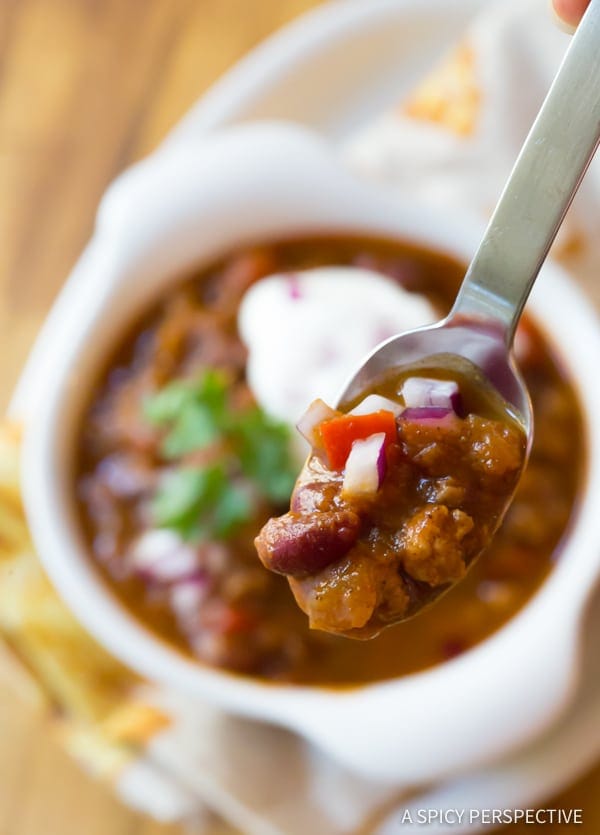 Pumpkin chili in a bowl with a spoonful of it above the bowl.