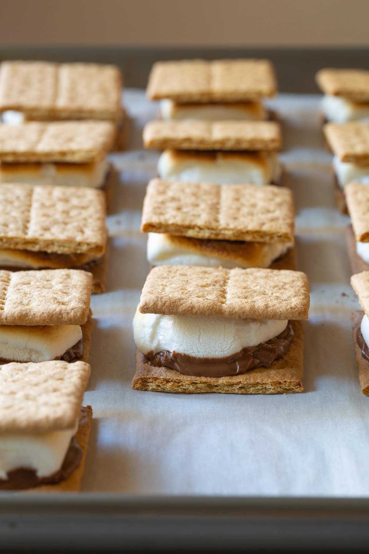 Baked s'mores lined up on a baking sheet.