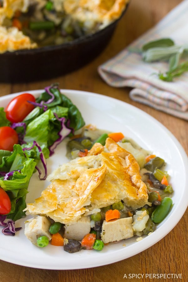 Slice of turkey pot pie on a plate next to a side salad.