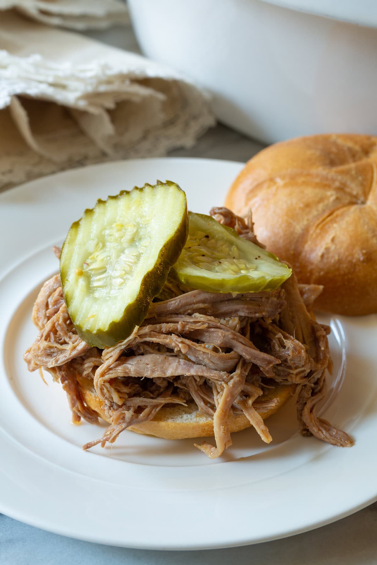 shredded smoked pulled pork on a bun with pickles