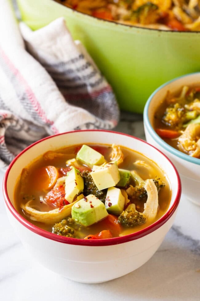 Detox Southwest Chicken Soup Recipe #ASpicyPerspective #Cleanse #Detox #Diet #Soup #Chicken Two bowls of detox soup topped with diced avocado.