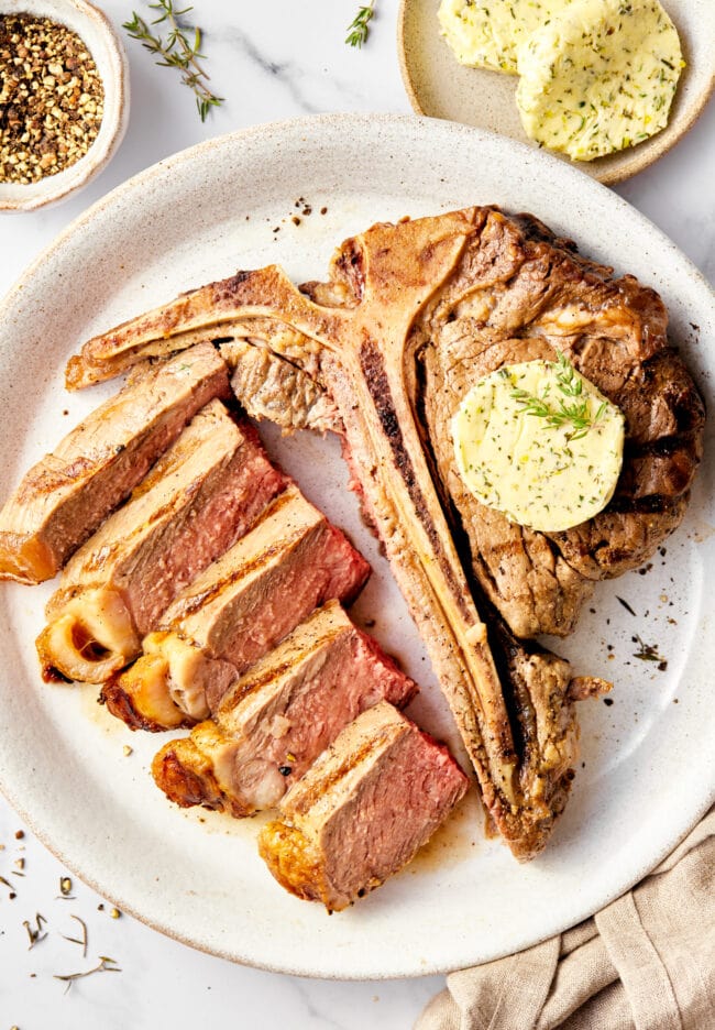 Porterhouse Steaks with Compound Butter | ASpicyPerspective.com Porterhouse steak recipe with herb butter topping - cut on plate