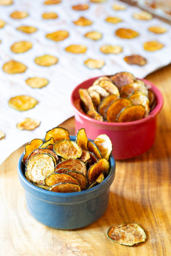 Baked zucchini chips from scratch served in two small ramekins.